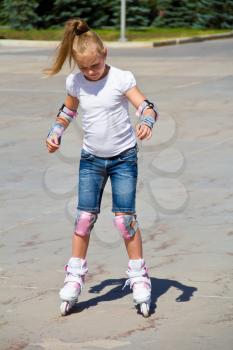 Learning girl on roller skates in summer