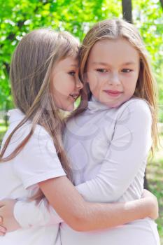 Photo of two smiling whispering girls in summer