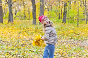 Photo of dancing and singing girl with two bouquets of sheets in autumn