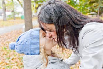 Photo of kissing mother and daughter in autumn