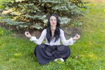European brunette woman on green grass in yoga pose