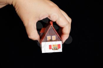 Image of dollhouse in human hand on black background