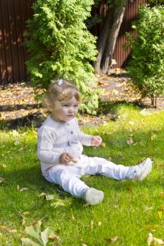 Baby girl with curly hair sitting on green grass