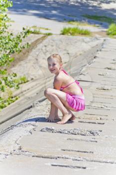 Cute jumping girl in pink swimsuit on the riverbank