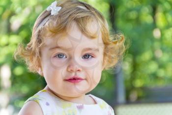 Portrait of cute baby girl with curly blond hair