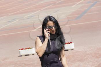European brunette in sunglass talking by cellular telephone