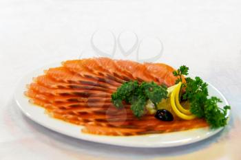 Healthy smoked fish on white platter with lemon slices