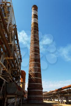 Tall chimney and pipelines on fuel refinery plant
