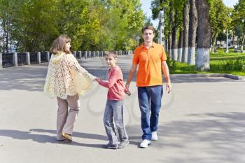 Happy walking family mother and son with father in summer embankment
