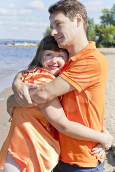 Husband embraces pregnant wife in summer embankment