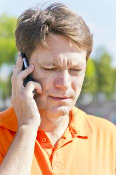Serious man talking by cellular in orange color