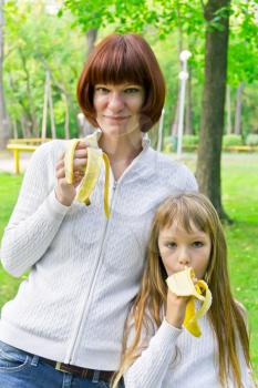 Photo of mother and daughter eating banana