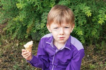 Horizontal photo of blond boy are eating icecream in summer 