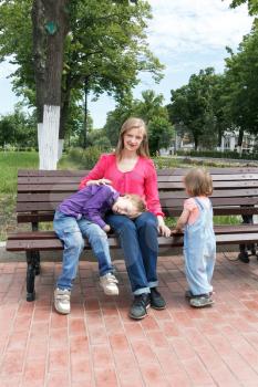 Mother with boy and baby girl has a rest in summer park