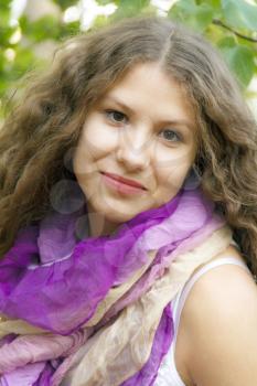 Young beautiful girl with curly hair in purple scarf