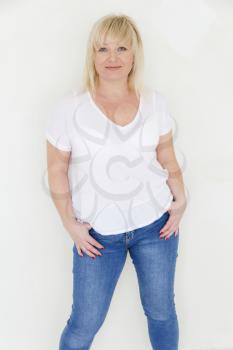 Blond woman in white and blue jeans stand inside empty room