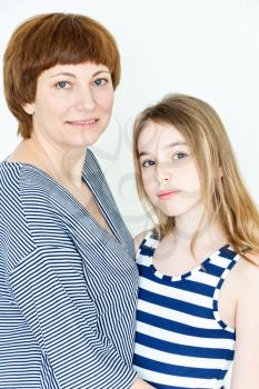 Portrait of happy mother and daughter near white wall