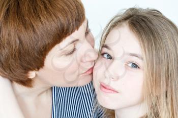 Portrait of kissing mother and daughter on white