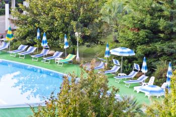Empty swimming pool with sun loungers in summer day