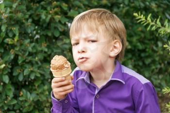 Horizontal photo of blond boy are eating icecream in summer