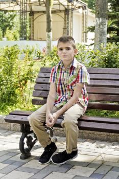 Cute brunette boy are sitting on the bench in summer