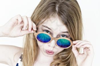 Girl eleven years old standing near white wall with green sunglasses