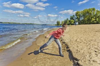 Boy in pink are throwing sand on a beach at the embankment side