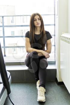 Brunette with long hair are sitting near window in gym