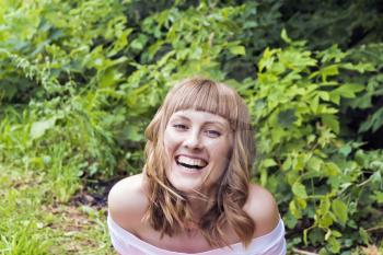 Horizontal portrait of laughing woman with blond hair on summer background