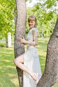 Bride with diadem and bare leg bent at the knee on summer background