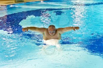 Big fat man in the swimming pool playing sports