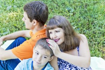Happy family with pregnant mother are sitting on green grass