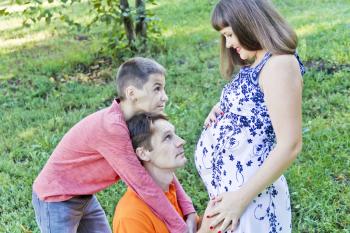 Happy father and son are kissing pregnant mother stomach