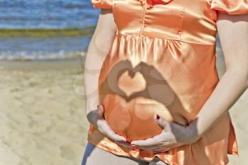 Man hands make heart on wife pregnant stomach