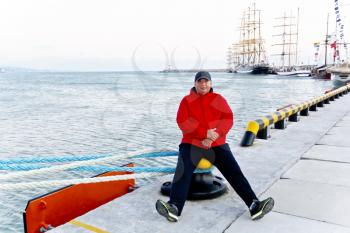 Big fat man in red jacket on ship and sea background