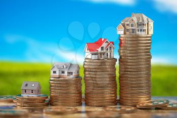 Houses of different size with on stacks of coins. Property, mortgage and real estate investment concept.  3d illustration