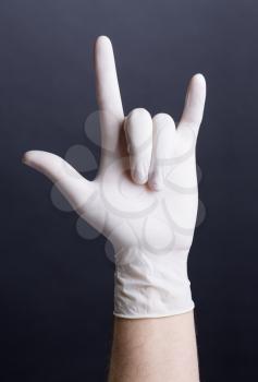 Male hand in latex glove (love sign) on dark background