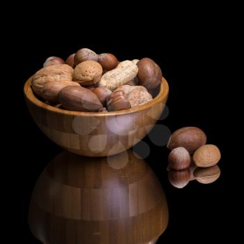 Nuts in wooden bowl. Bulrap and green background.
