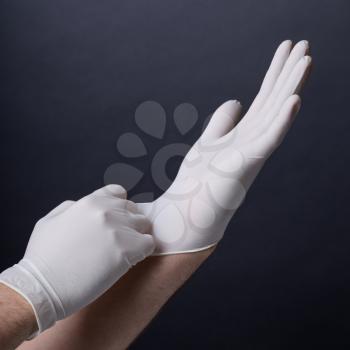 Male hands putting on latex gloves on dark background