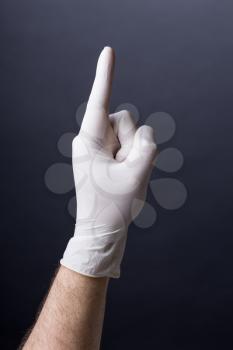 Male hand in latex glove pointing up on dark background