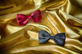 Red and black bow ties on draped golden satin