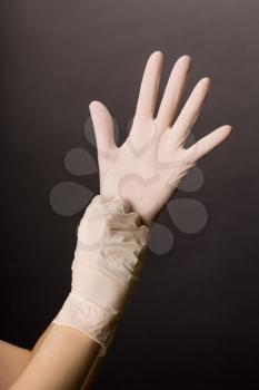 Female hands in golves. Doctor or nurse putting on latex gloves. Sanitary, healthcare, medical clothing. Dark background