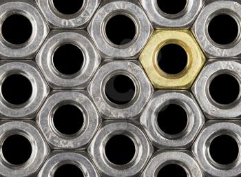 Golden screw nut in steel nuts pattern isolated on black. Abstract background. 