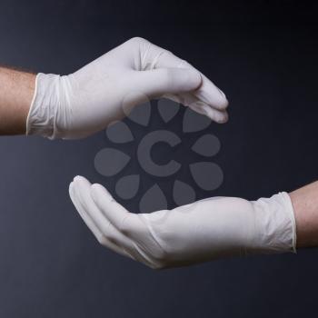 Male hands in latex gloves encircling, on dark background. Place for a concept.