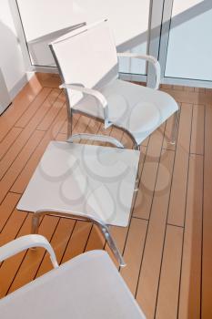 two textile chairs and table on balcony of cruise liner