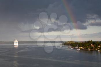 white cruise liner and rainbow in rain during sunshine in Baltic sea