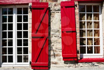  windows with red wooden shutter in old breton house