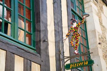 old wood harlequin figure under pizzeria on medieval house