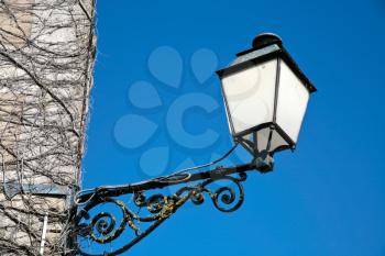 lantern on wall overrun with ivy with blue sky background