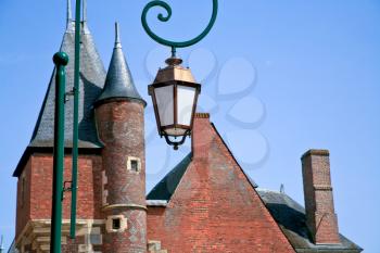 bronze street lamp and red brick roofs of medieval town Gien, France